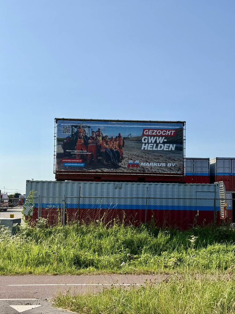 Spandoek "Gezocht GWW-helden" op een containerstapel